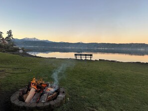 A lakeside view with a fire pit, bench, and mountains in the background. - 2-bedroom condo with pool, hot tub, WiFi, fitness room in welcoming Union, WA (Union)