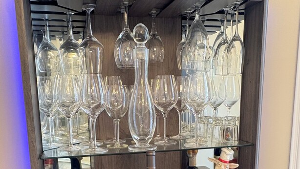Un buffet en bois contenant de nombreux verres et bouteilles de vin.