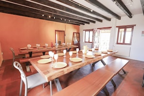 Un espace repas avec de longues tables en bois, des bancs et des chaises.