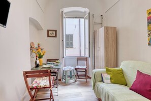 A compact room with a dining table, chairs, a sofa, and a window with a view.