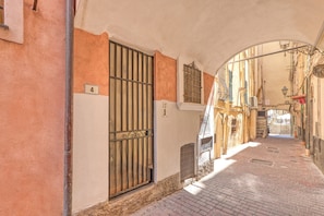 A narrow alleyway with a metal gate, a number '4' sign, and a brick-paved path.