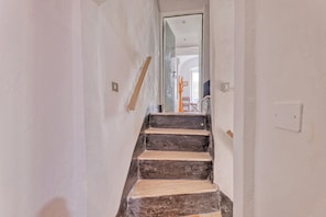A staircase leading to a room with white walls, a visible door, and a light switch on the wall.