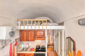 Una cocina compacta con armarios de madera, un fregadero, una estufa y un refrigerador pequeño.
