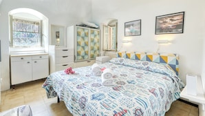Un dormitorio con cama, cómoda, armario, ventana y candelabro.