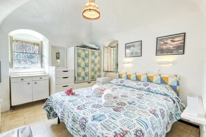 Un dormitorio con cama, cómoda, armario, ventana y candelabro.