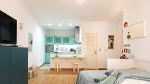 Une chambre d’hôtel de taille réduite, comprenant un lit, une télévision, une kitchenette et une salle de bain.