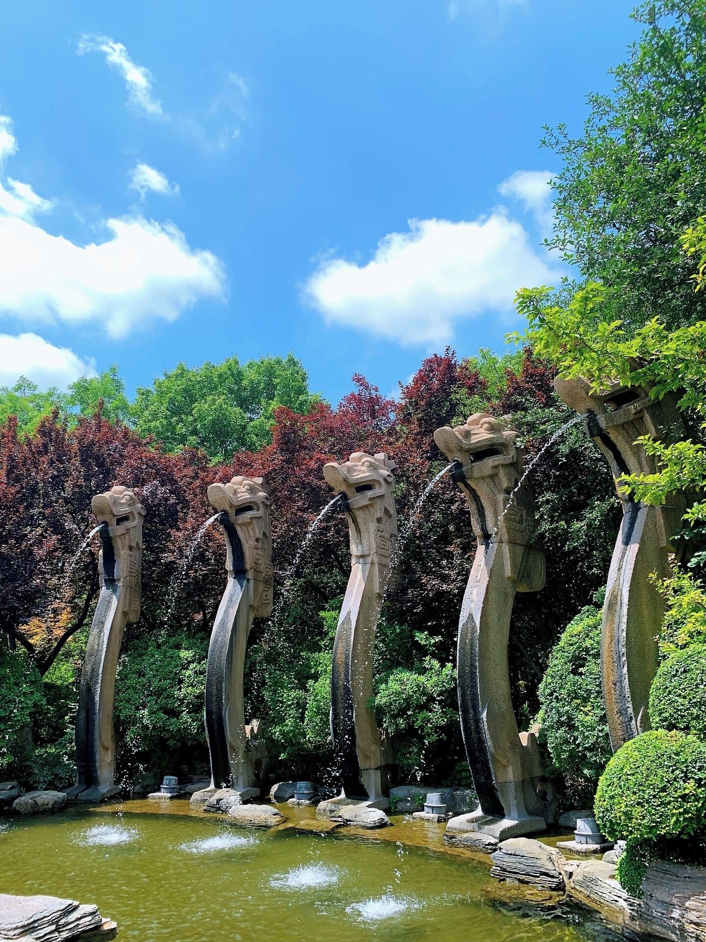 A garden with a series of stone water spouts and a pond.