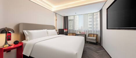 Une chambre d’hôtel moderne avec un grand lit, un bureau avec une lampe, une chaise et un téléviseur.