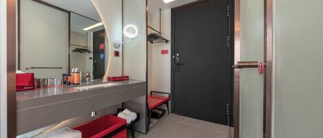 A modern bathroom with a large mirror, a vanity with a red towel rack, and a black door.
