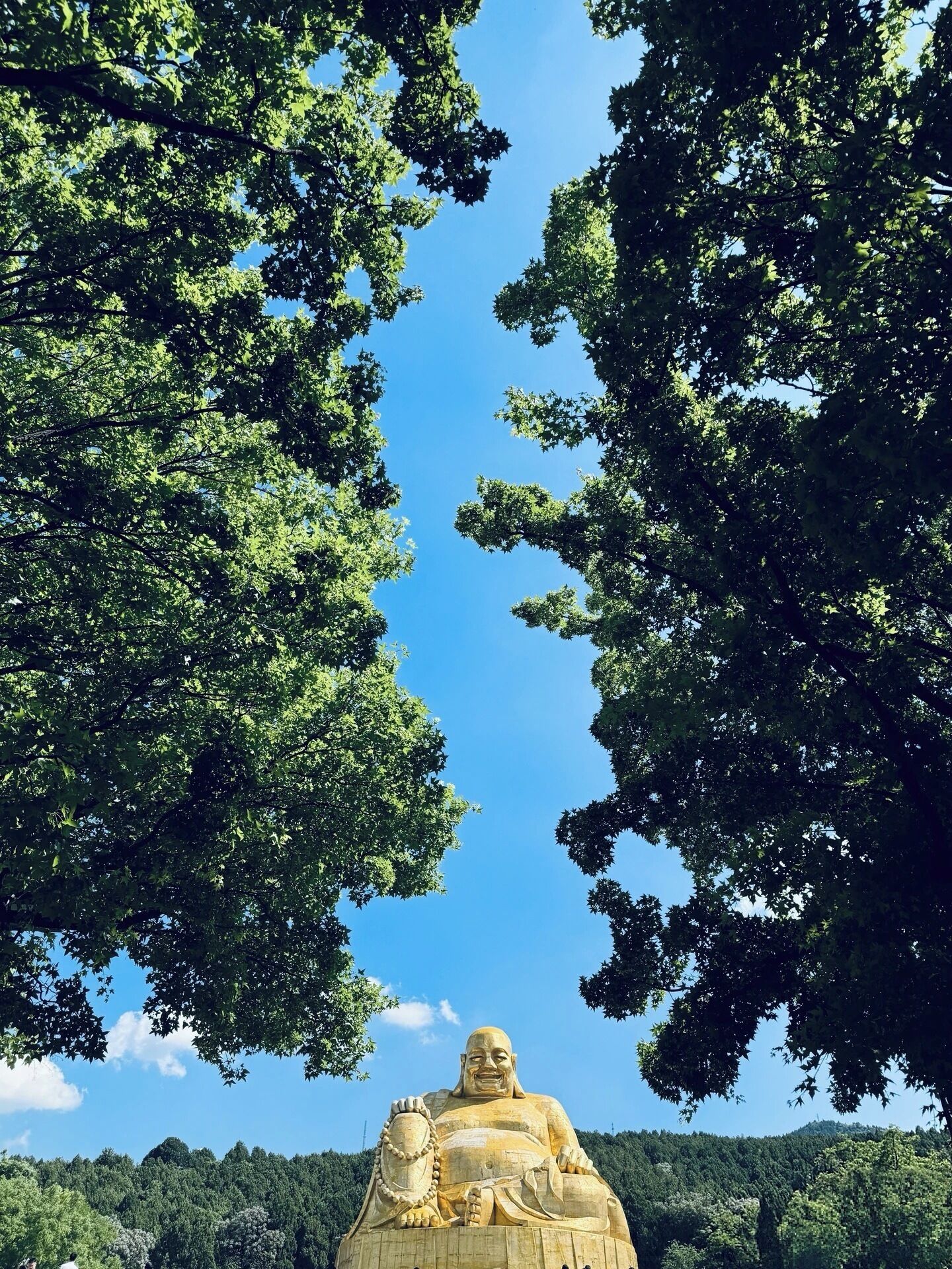 A large golden statue surrounded by lush green trees.