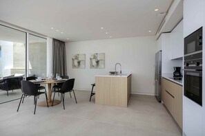 Eine moderne Küche mit Essbereich, ausgestattet mit einem Holztisch, schwarzen Stühlen und einer kleinen Kochinsel mit Spüle.