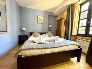 A hotel room with a bed, bedside lamps, a framed picture on the wall, and a window with curtains.