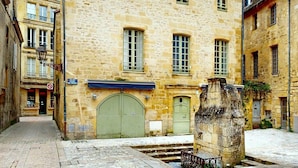 A stone building with a green door and windows, situated in a narrow street with cobblestone pavement. - Les Fables - Air-conditioned and downtown (Sarlat-la-Canéda)