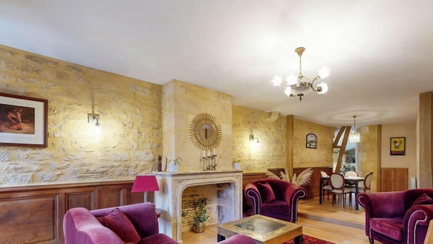 A cozy living room with a fireplace, plush red sofas, and a chandelier. - Les Fables - Air-conditioned and downtown (Sarlat-la-Canéda)