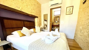 A hotel room with a large bed, a nightstand, a wardrobe, and a mirror. - Les Fables - Air-conditioned and downtown (Sarlat-la-Canéda)