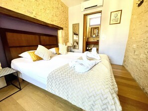 A hotel room with a large bed, a nightstand, a wardrobe, and a mirror. - Les Fables - Air-conditioned and downtown (Sarlat-la-Canéda)