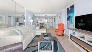 Una sala de estar moderna con un sofá blanco, una mesa de centro y un televisor sobre un mueble.