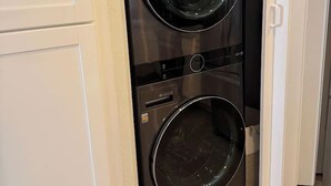 Ein kleiner, moderner Waschraum mit integriertem Waschmaschine und Trockner, mit einer eleganten schwarzen Oberfläche und einer kleinen Bedienkonsole.