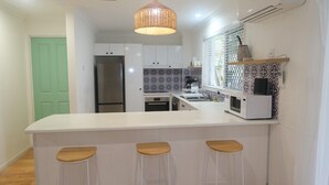 Cocina moderna con armarios blancos, una isla central con taburetes, una lámpara colgante y un salpicadero con diseño.