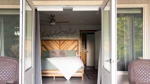 A bedroom with a bed, a ceiling fan, and a branch decoration on the wall.