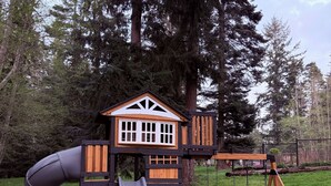 A playground with a slide, swing set, and a playhouse.
