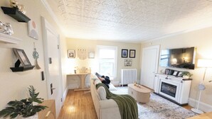 Un salon avec un canapé, une cheminée, un téléviseur et une plante.