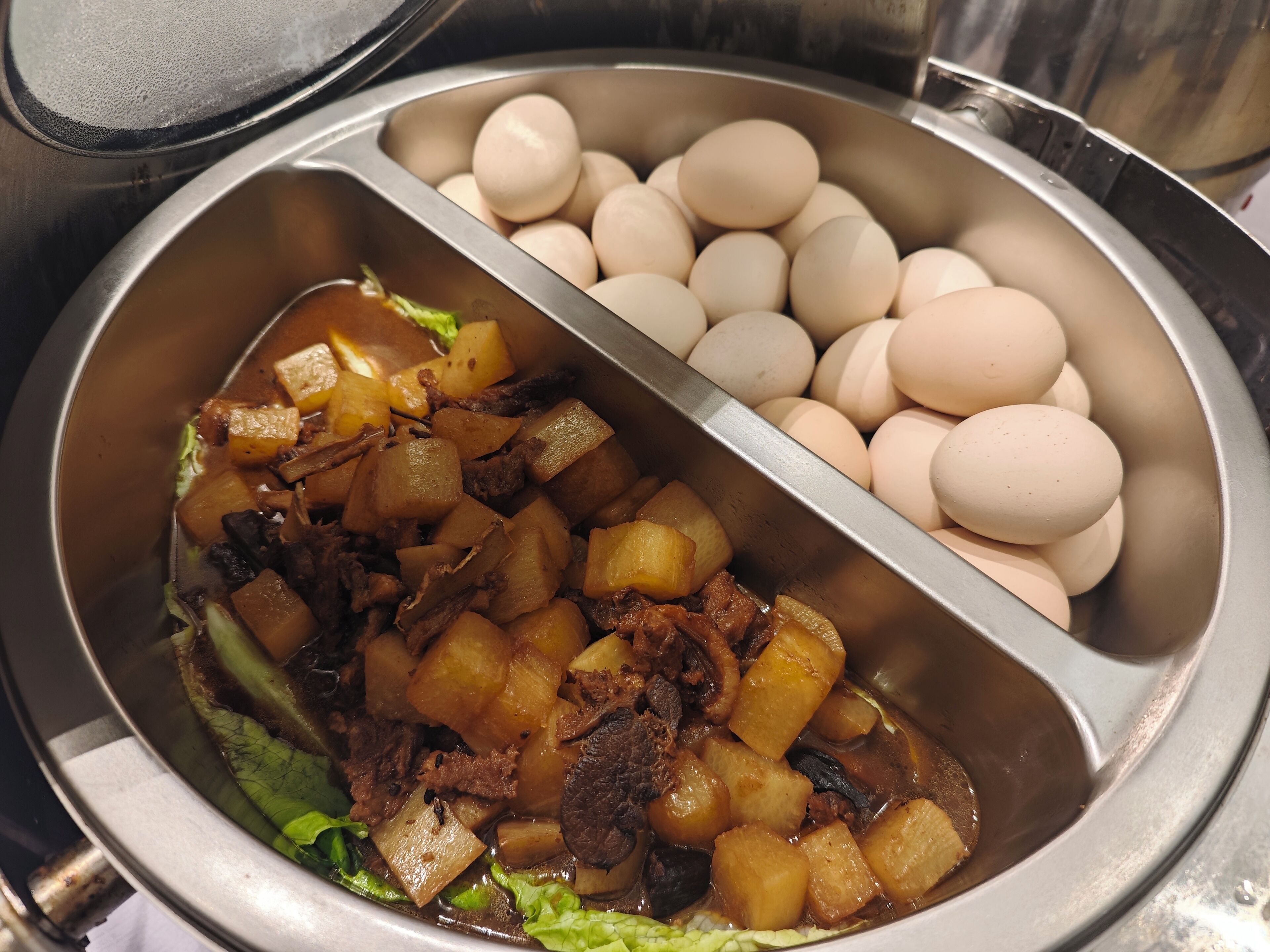 Un bufé con una variedad de platos, incluyendo carne, papas y huevos.