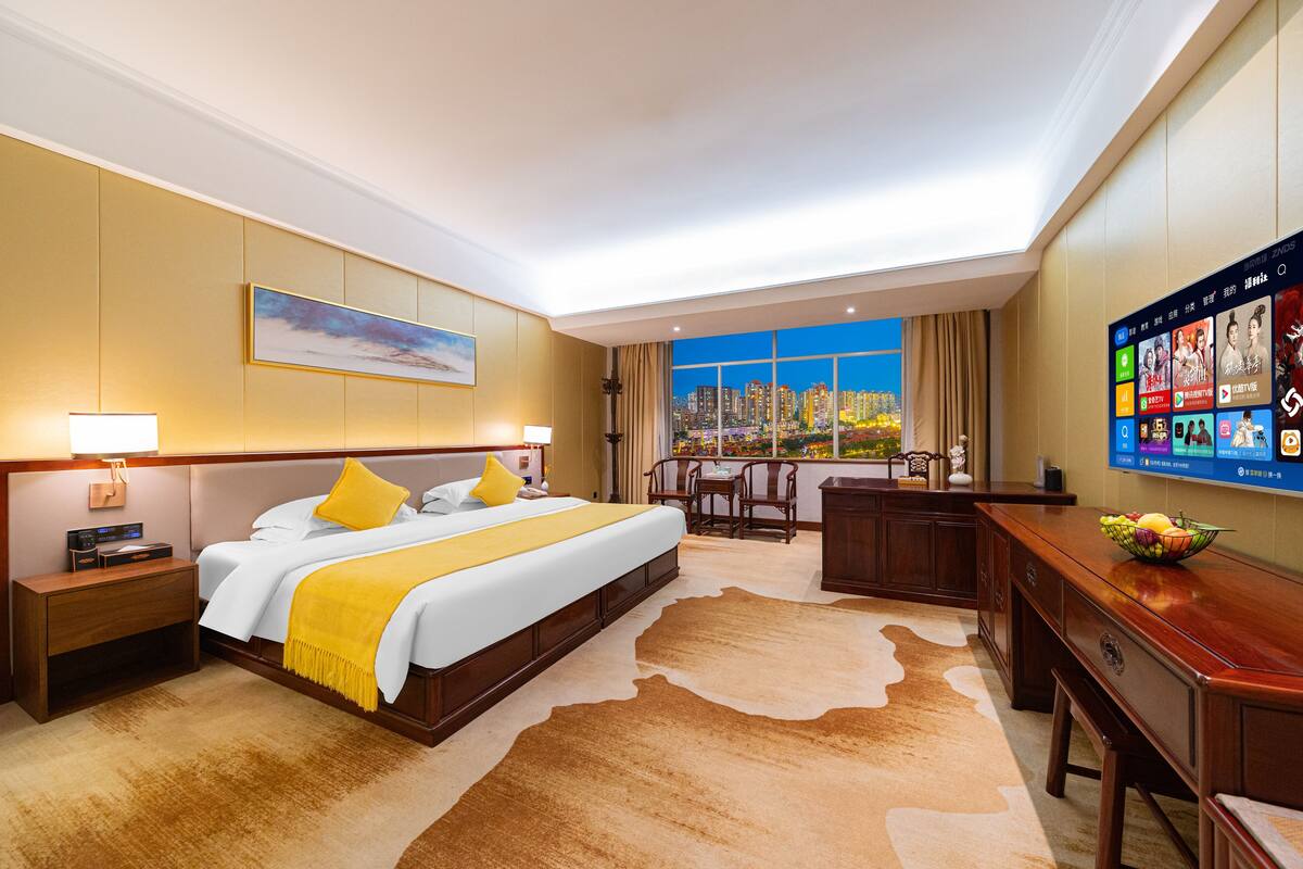 Una camera d'albergo con un letto grande, una scrivania, una TV e vista sulla città.
