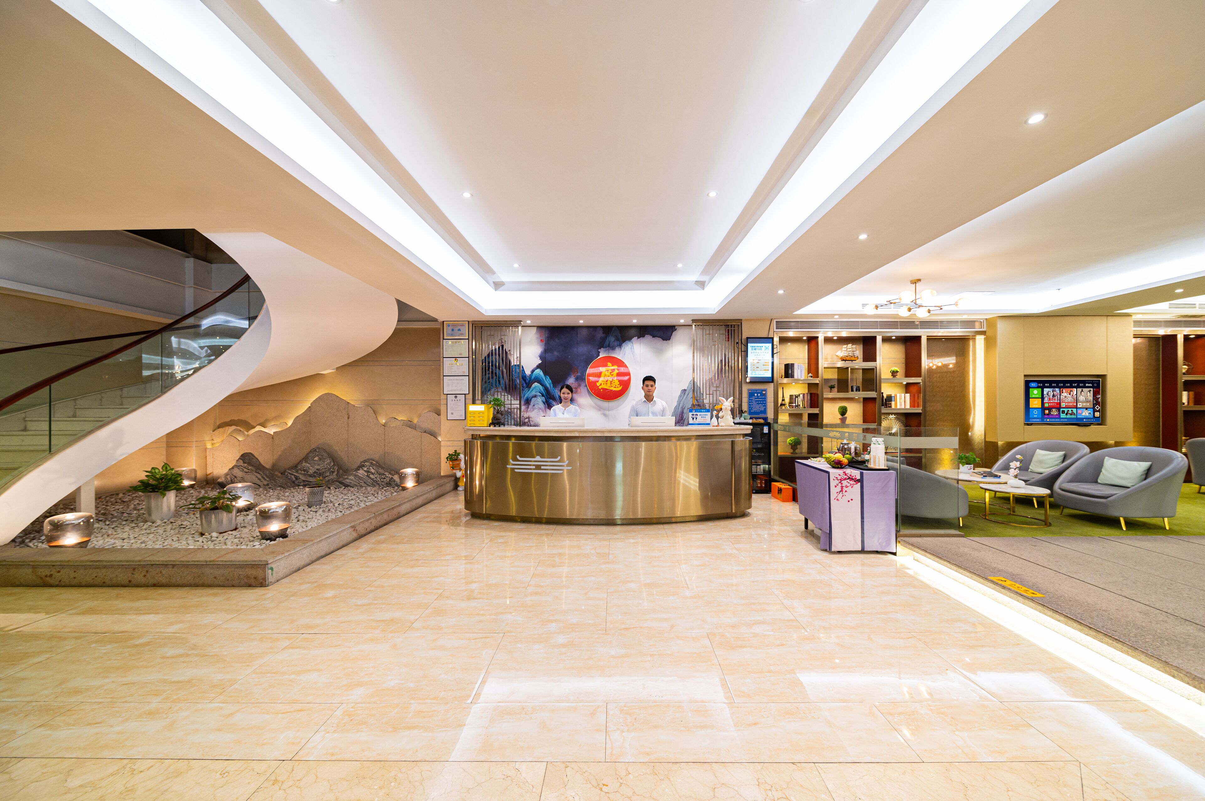 Um hall de hotel moderno com balcão de recepção, área de estar e escadaria.
