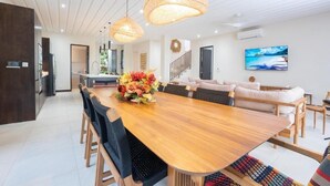 Un comedor moderno con una mesa de madera, sillas negras y lámparas colgantes tejidas.