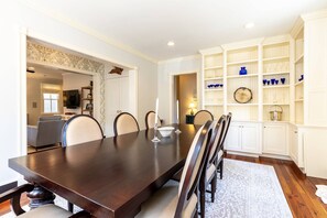 A dining room with a dark wooden table, white chairs, and a patterned rug. - Spacious Historic Home with Private Parking in the Heart of Downtown Annapolis (Annapolis)