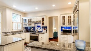 Una cocina moderna con armarios blancos, encimeras de granito y salpicadero con azulejos azules.