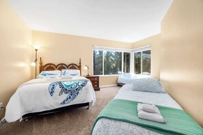 A bedroom with two beds, a large window, and a nightstand with a lamp. - Sand Dollar Beach Home - Stunning views! (La Selva Beach)