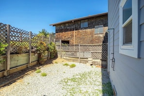 A residential property with a wooden exterior, a gravel driveway, and a wooden fence.