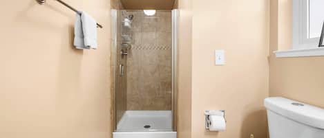 A bathroom with a shower, toilet, and towel rack.