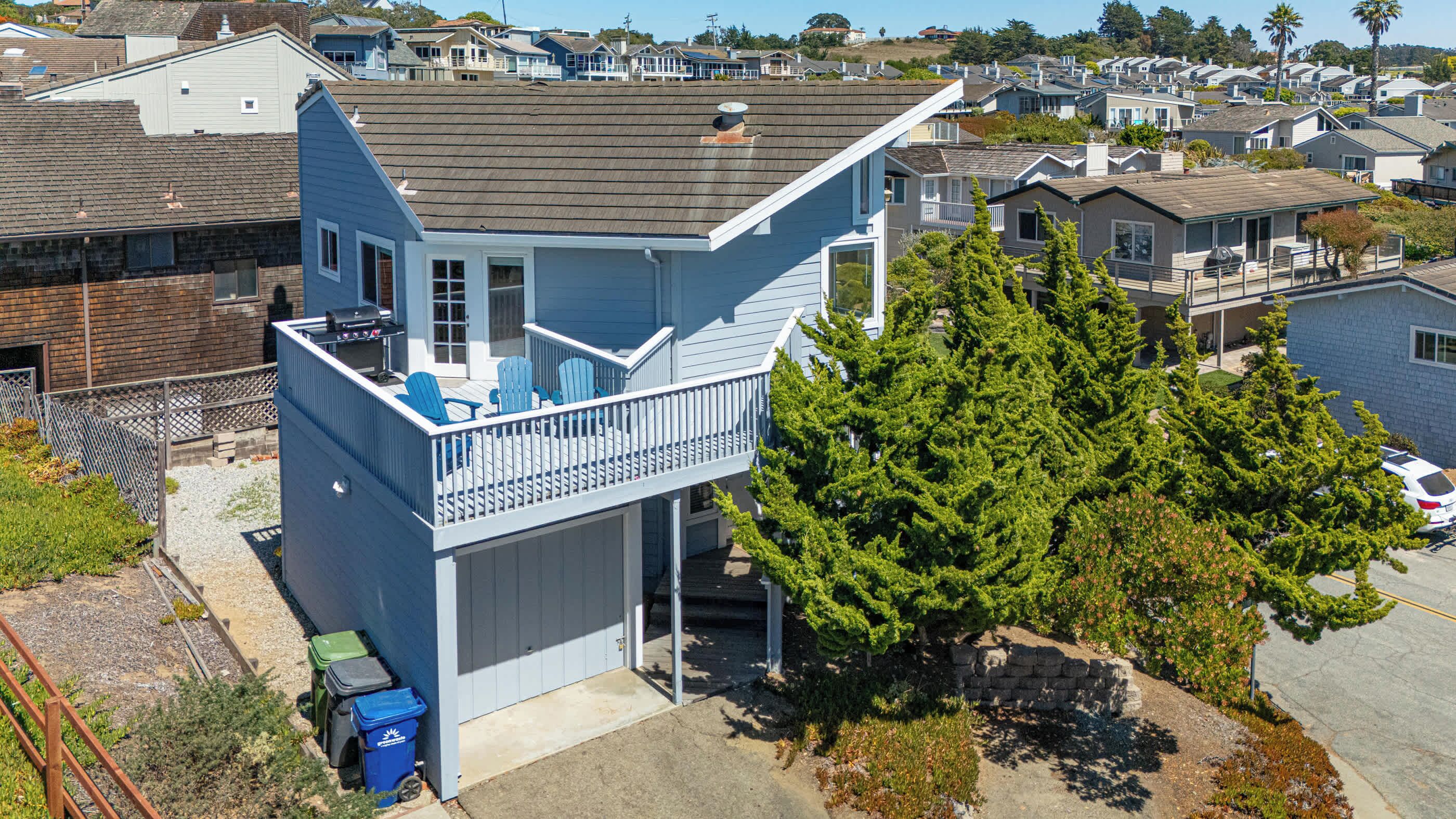 A two-story house with a balcony, a garage, and a large tree in front.