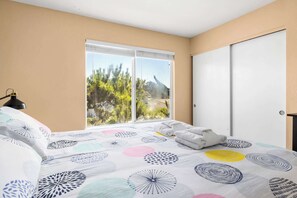 A bedroom with a bed, a window with a view of trees and a mountain, and a door.