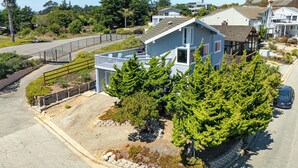 Un quartier résidentiel avec une maison à deux étages, une allée bordée d’une clôture et une voiture garée.