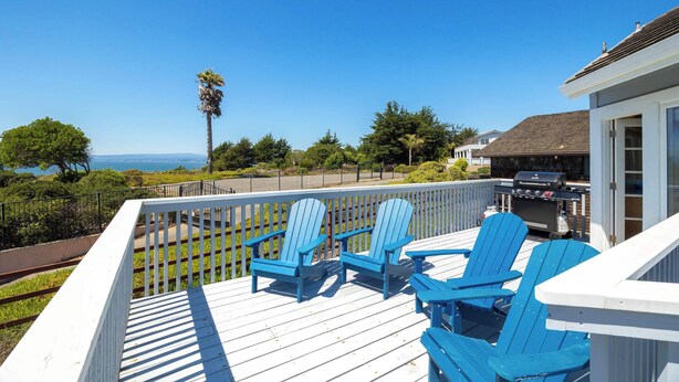 Une terrasse avec des chaises Adirondack bleues et un barbecue, offrant une vue panoramique.