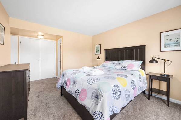 A bedroom with a bed, a dresser, a nightstand, and a door.