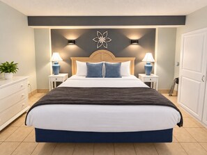 A bedroom with a large bed, two bedside tables, a nightstand, a decorative wall piece, and a door. - Ocean Breeze Hideaway (Myrtle Beach)