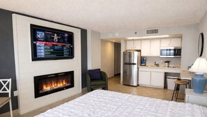 Une chambre dotée d’une cheminée, d’une télévision, d’un coin cuisine et d’un lit.