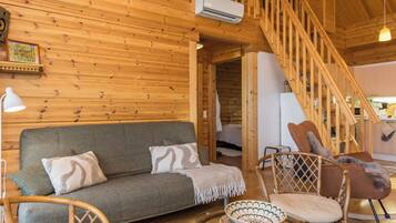 Een houten interieur met een bank, stoelen, een trap en een airconditioning.