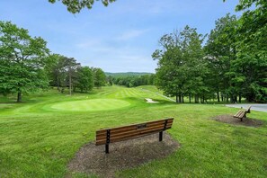 Ein Park mit Golfplatz, einer Holzbank und Bäumen.