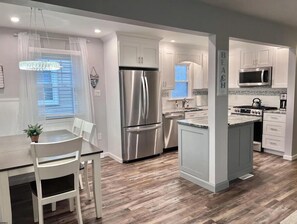 Una cocina moderna con armarios blancos, electrodomésticos de acero inoxidable y piso de madera.