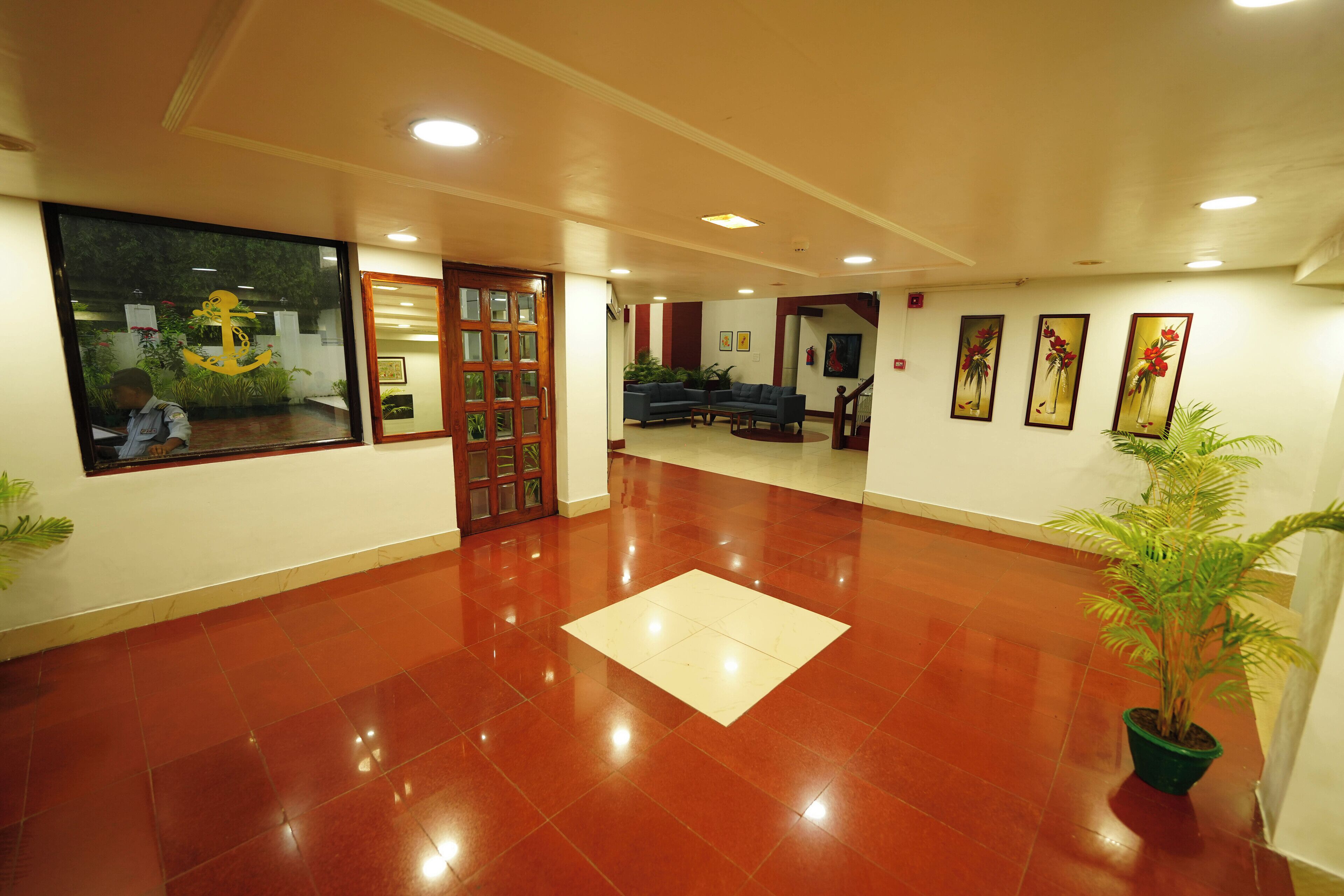 A spacious lobby with a polished red floor, a reception desk, and a large window with a view of the outside.