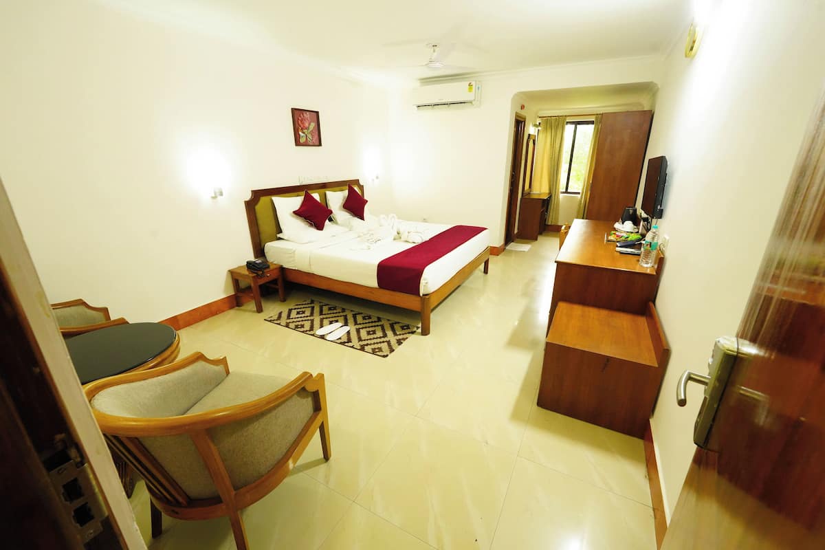 A hotel room with a bed, a desk, a chair, and a TV.