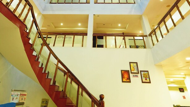 Un atrio de varios niveles con una escalera central, ventanas amplias y un techo alto.