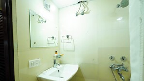Un baño con lavamanos, espejo, ducha y toallero.