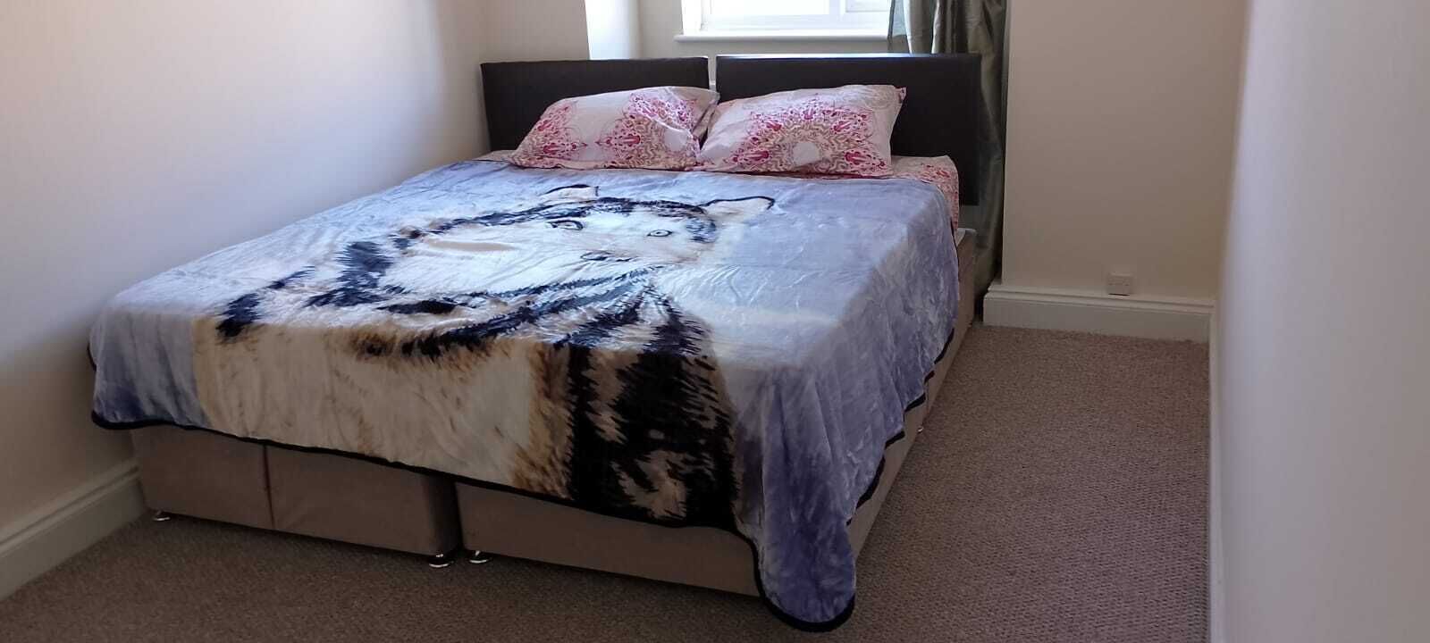 Ein Bett mit einem gemusterten Überwurf, einem Kopfteil und zwei Kissen.